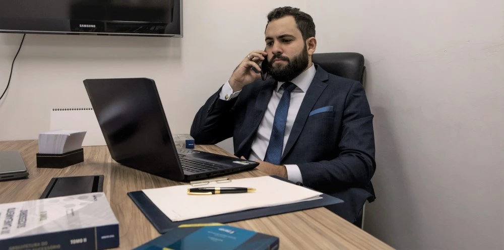 avogado trabalhando e falando ao telefone sentado em frente ao computador no escritório de advocacia